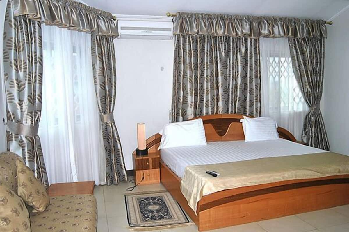 A bedroom with a bed, curtains, a bedside table, and a rug.