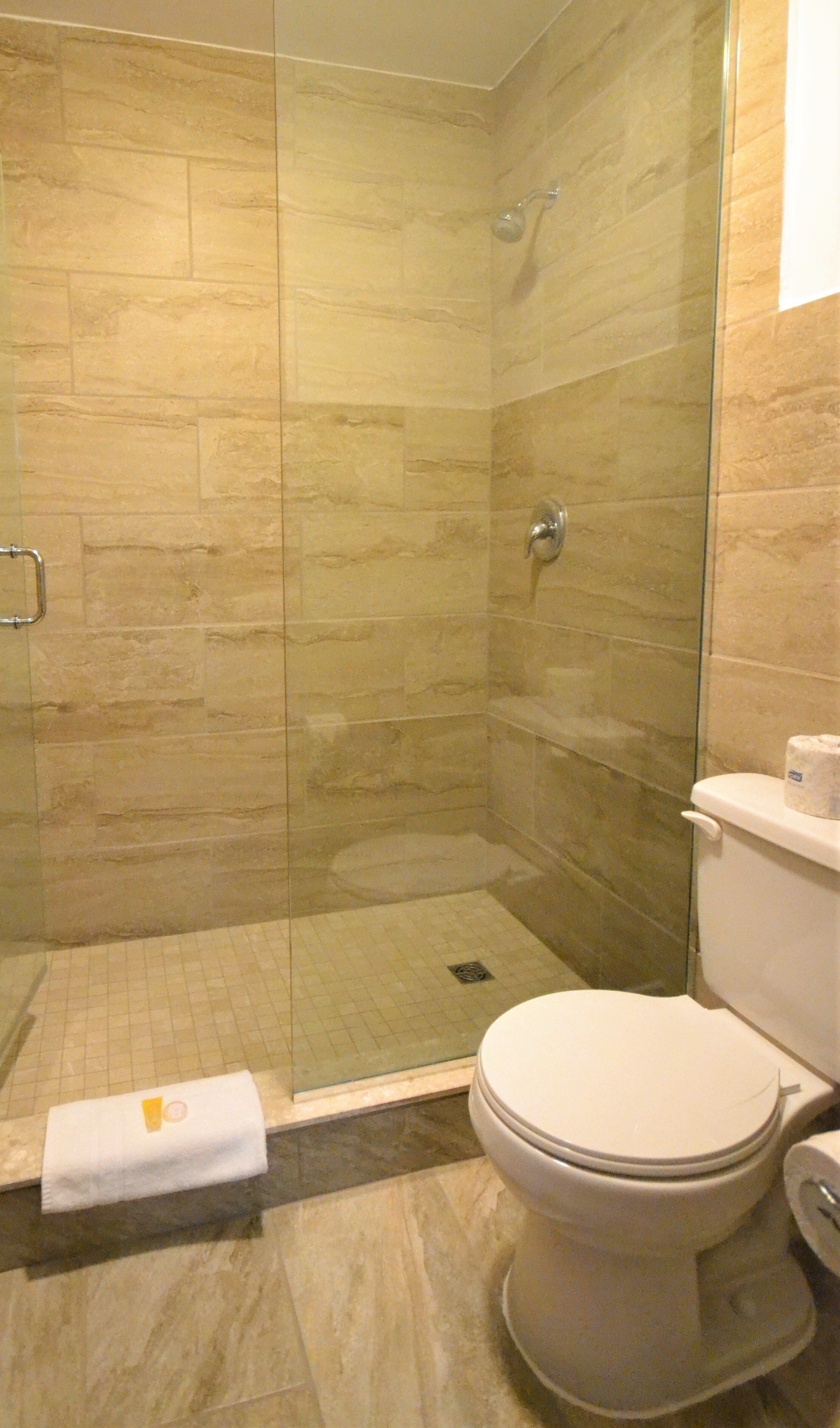 A bathroom with a glass-enclosed shower, a toilet, and a towel on the floor.