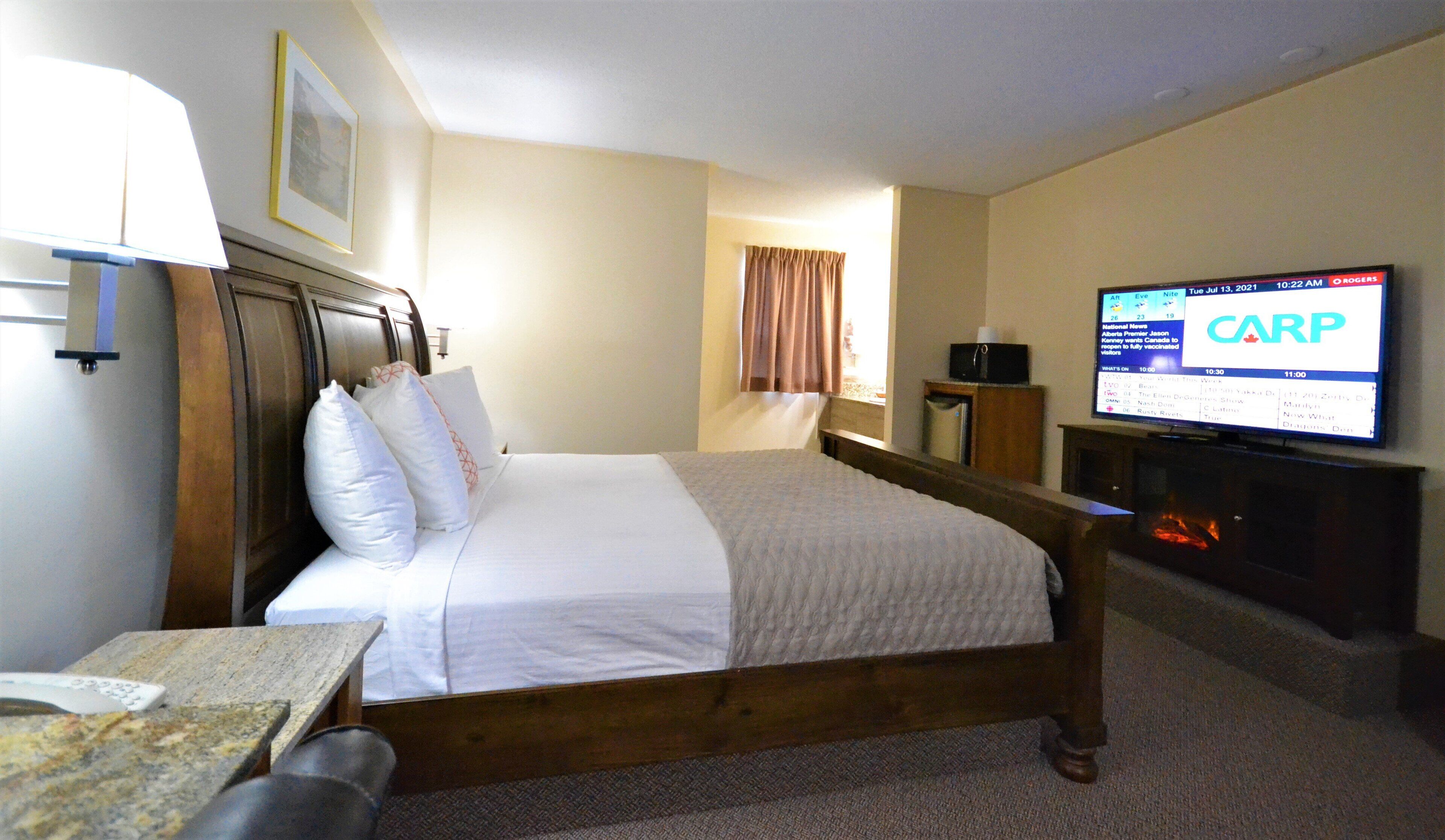A hotel room with a bed, a television displaying the 'CARP' channel, a desk with a remote control, and a wooden headboard.