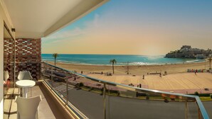 Un balcón con vista a una playa y un edificio lejano.