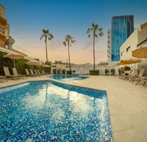 Una piscina al aire libre, sombrillas, sillones reclinables de piscina