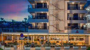 Un hotel con varios balcones, mobiliario exterior y una zona de bar.
