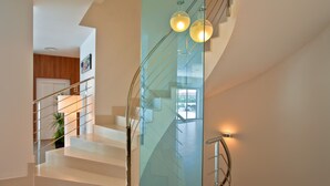 Una escalera moderna con barandillas de vidrio e iluminación integrada, que sube a un nivel superior.