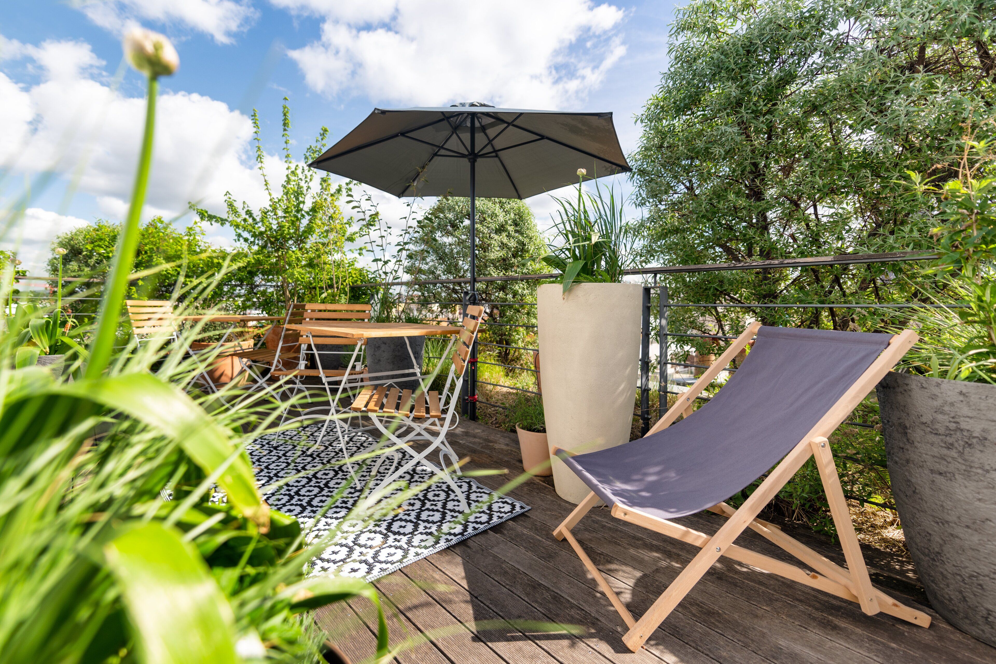 A wooden deck with a table and chairs, a hammock, and a large umbrella.