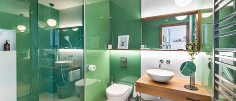 A modern bathroom with a glass shower enclosure, a white toilet, and a wooden vanity with a bowl sink.