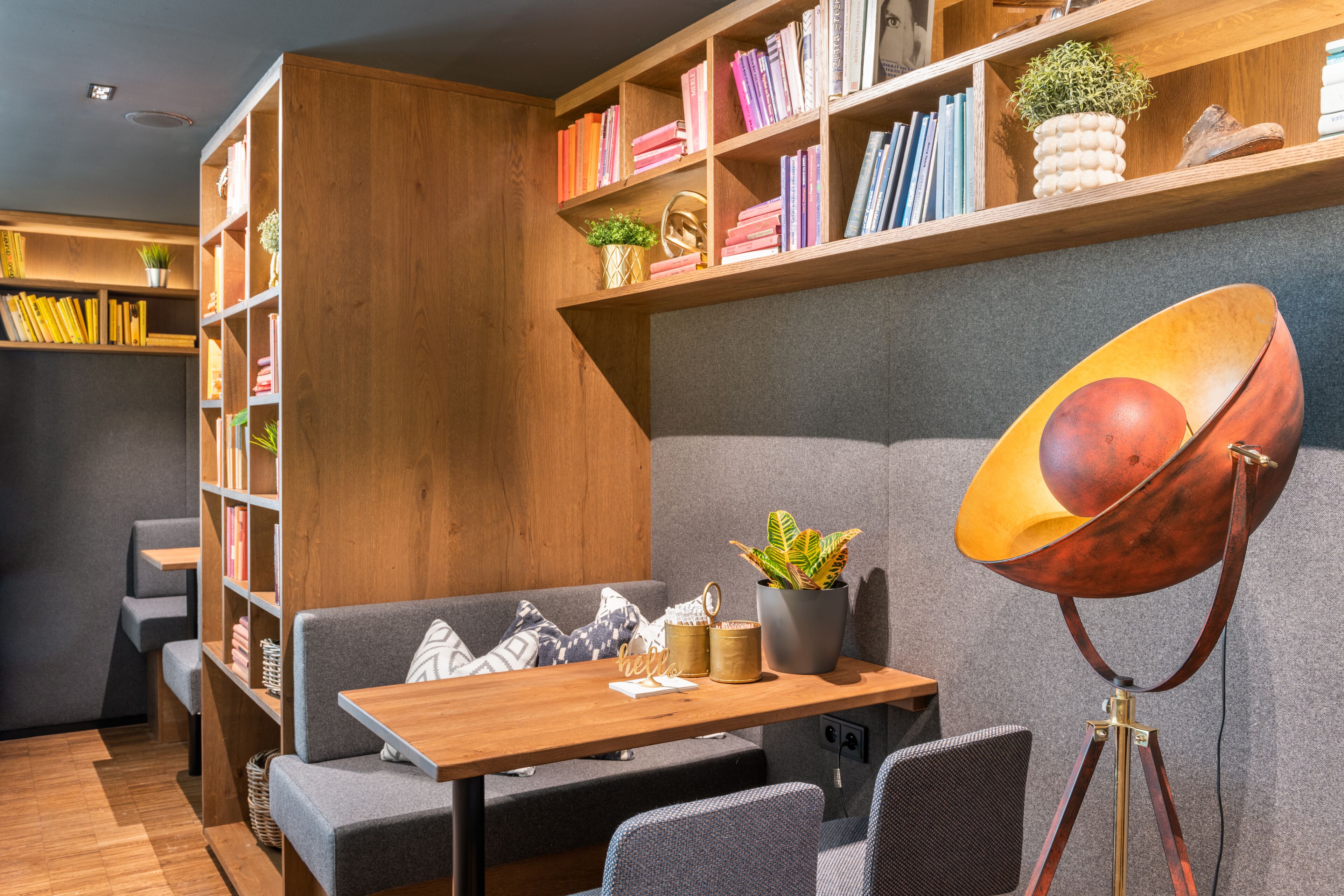 A cozy reading nook with a wooden bookshelf, a comfortable sofa, a small table, and a floor lamp.