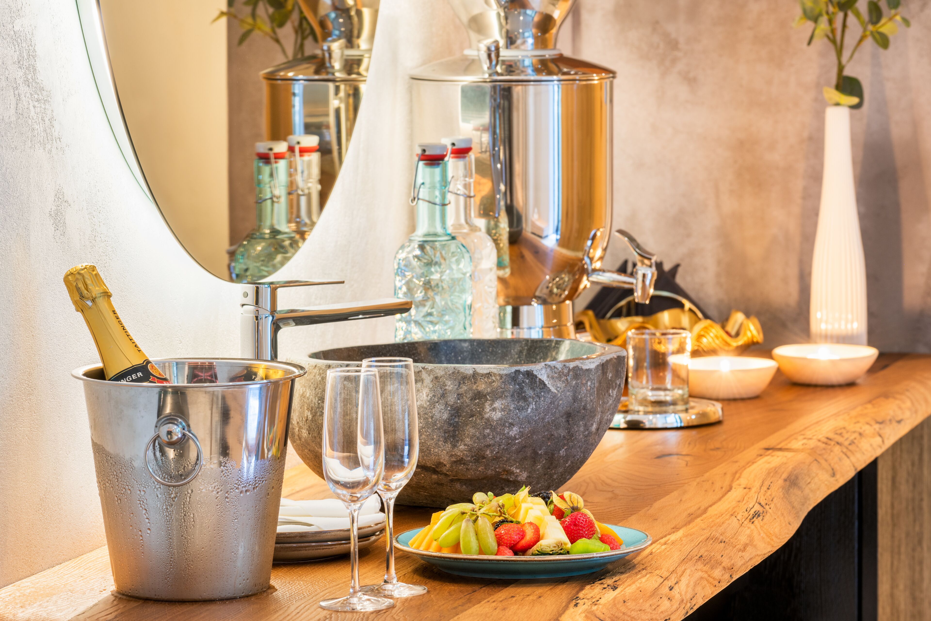 A bar area with a large stone bowl, a champagne bottle, and a fruit plate.