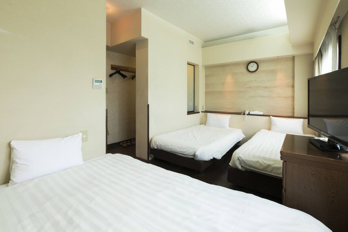 Una habitación de hotel con dos camas, un televisor y un reloj en la pared.