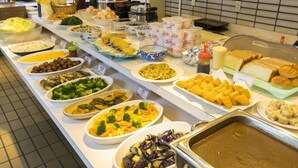 Un bufé con diversos platos, entre ellos pasta, ensaladas y pan.