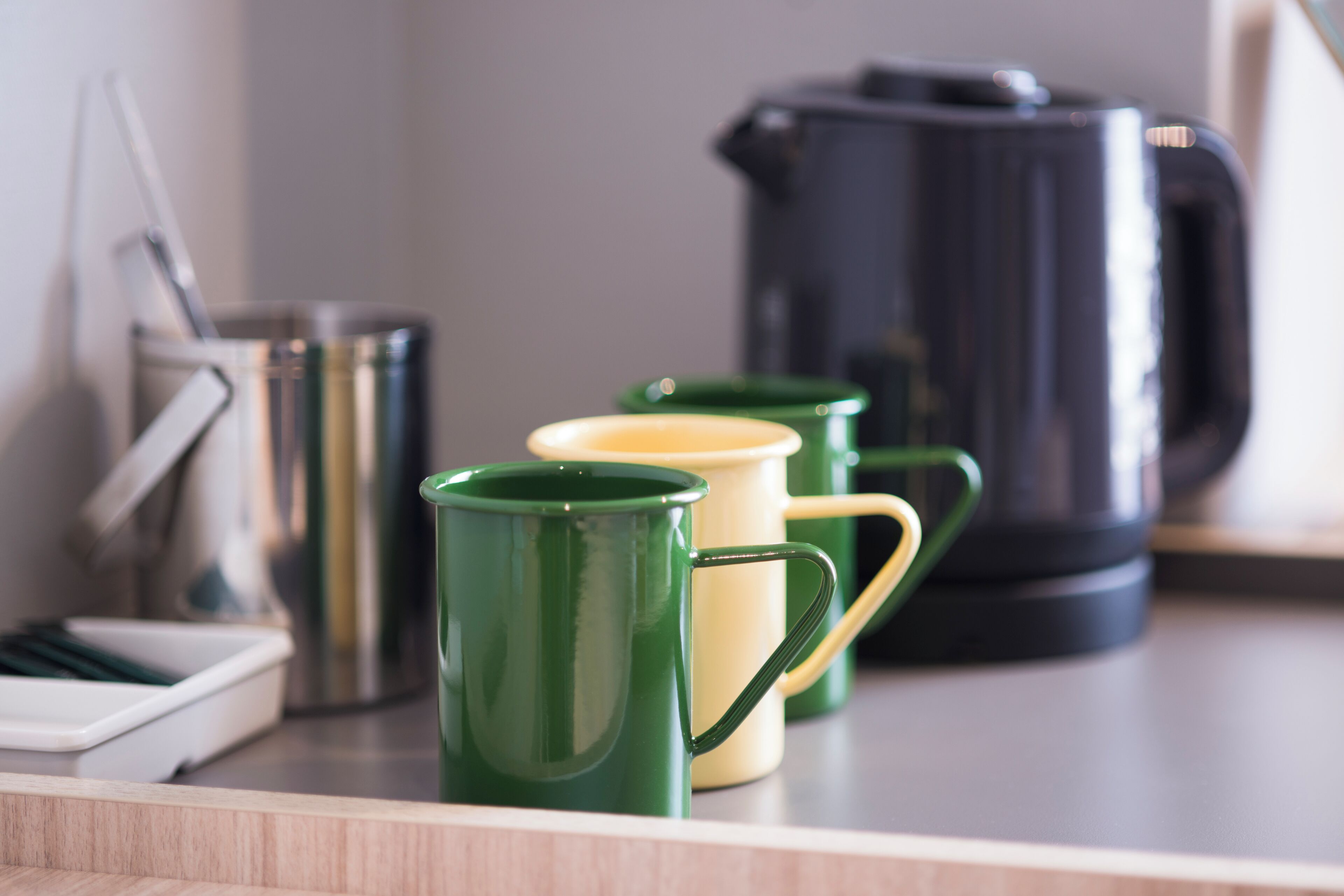 Una encimera de cocina con una cafetera, un hervidor y dos tazas.