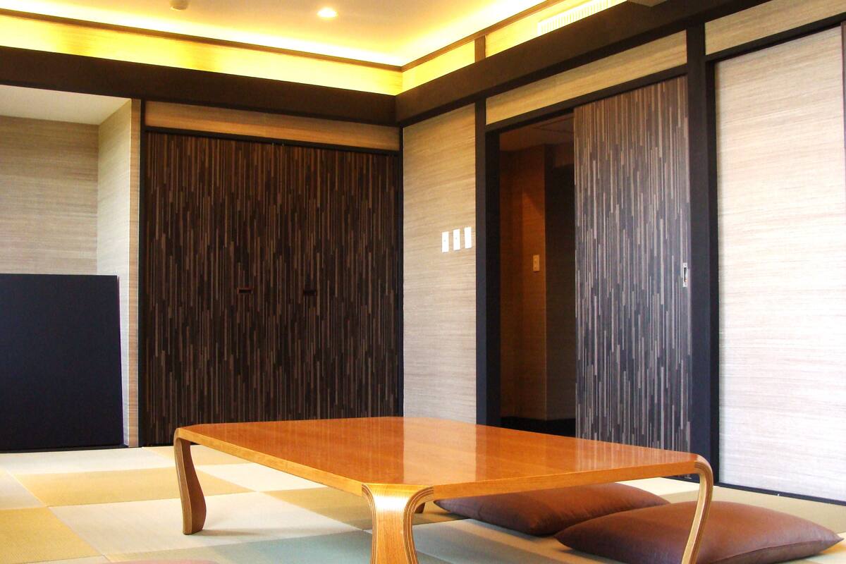 A modern room with a wooden table, tatami mats, and sliding doors.
