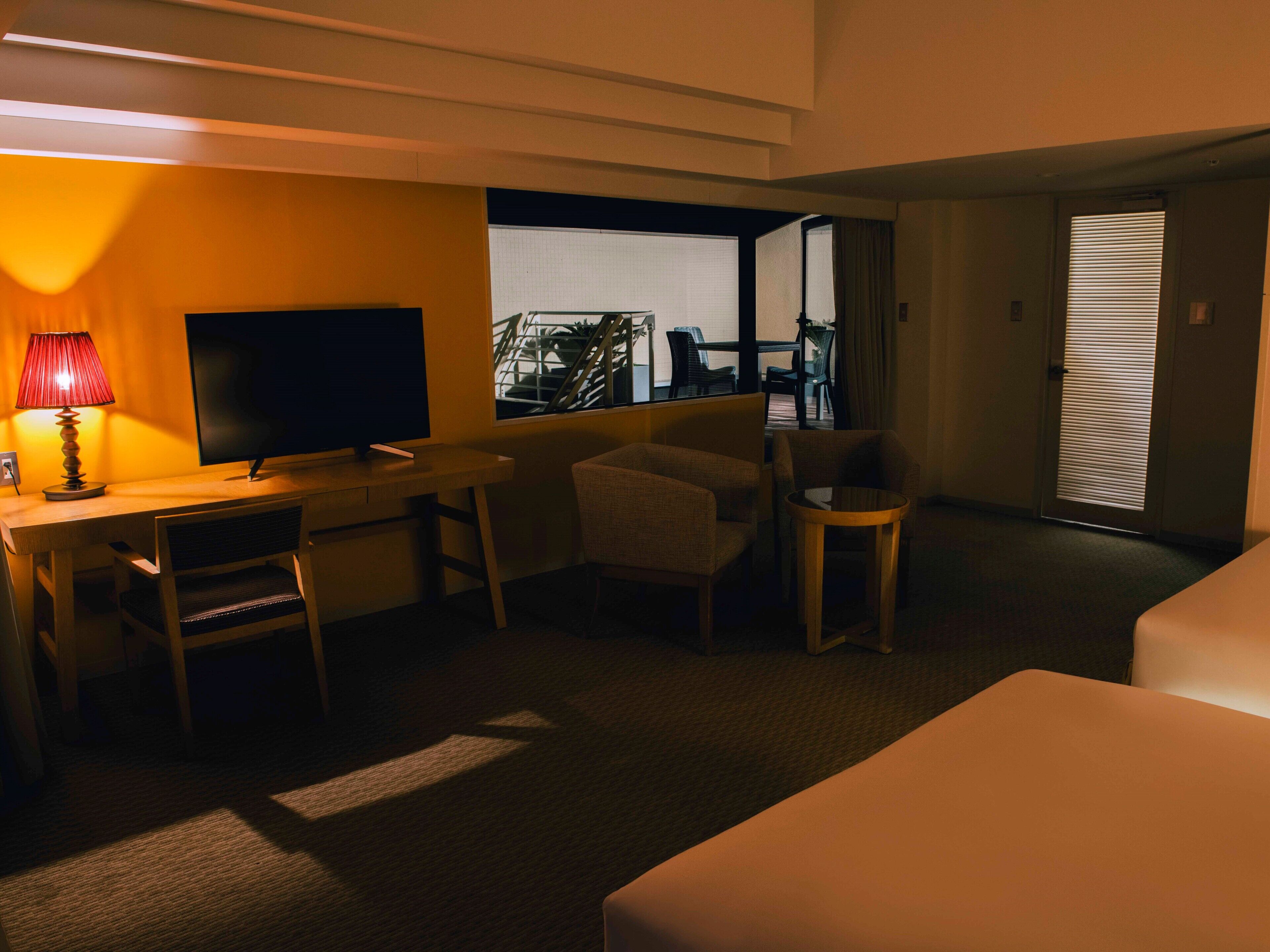 A hotel room with a desk, a TV, a sofa, and a bed.