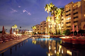 A swimming pool with lounge chairs and umbrellas, surrounded by palm trees and a multi-story hotel building. - The Luigans Spa and Resort (Fukuoka)