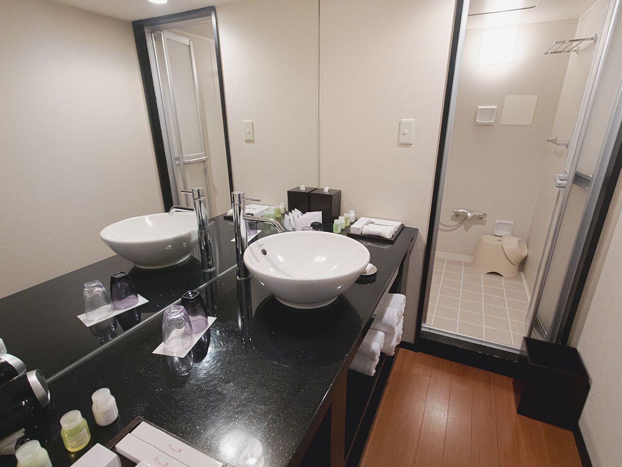 Une salle de bain moderne avec deux lavabos, un miroir et un espace douche.