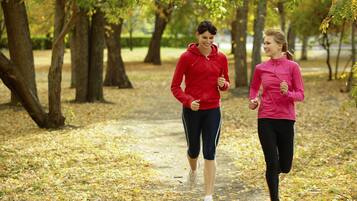 Two people jogging on a leaf-covered path in a park.