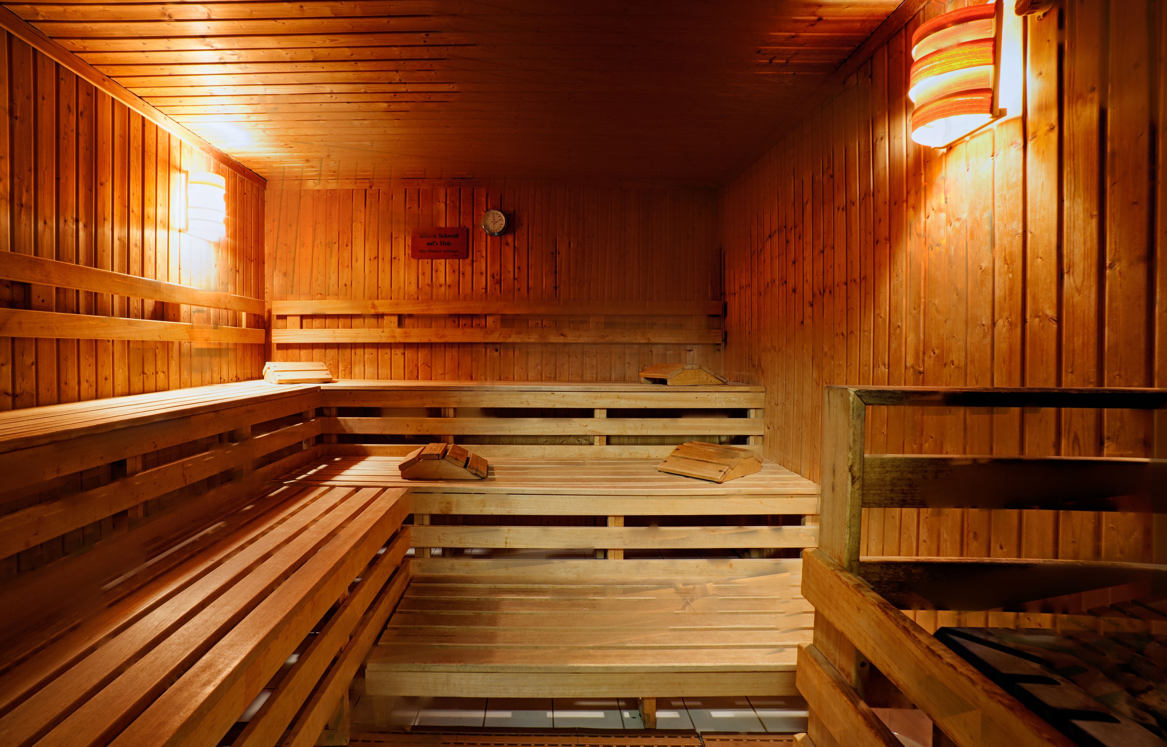 Een sauna met houten banken en een houten wand met een klok.