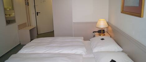 Una habitación de hotel con una cama, una mesita de noche con lámpara, un teléfono y un cuadro en la pared.