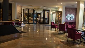 A spacious lobby with a polished floor, seating area with chairs, and a reception desk.