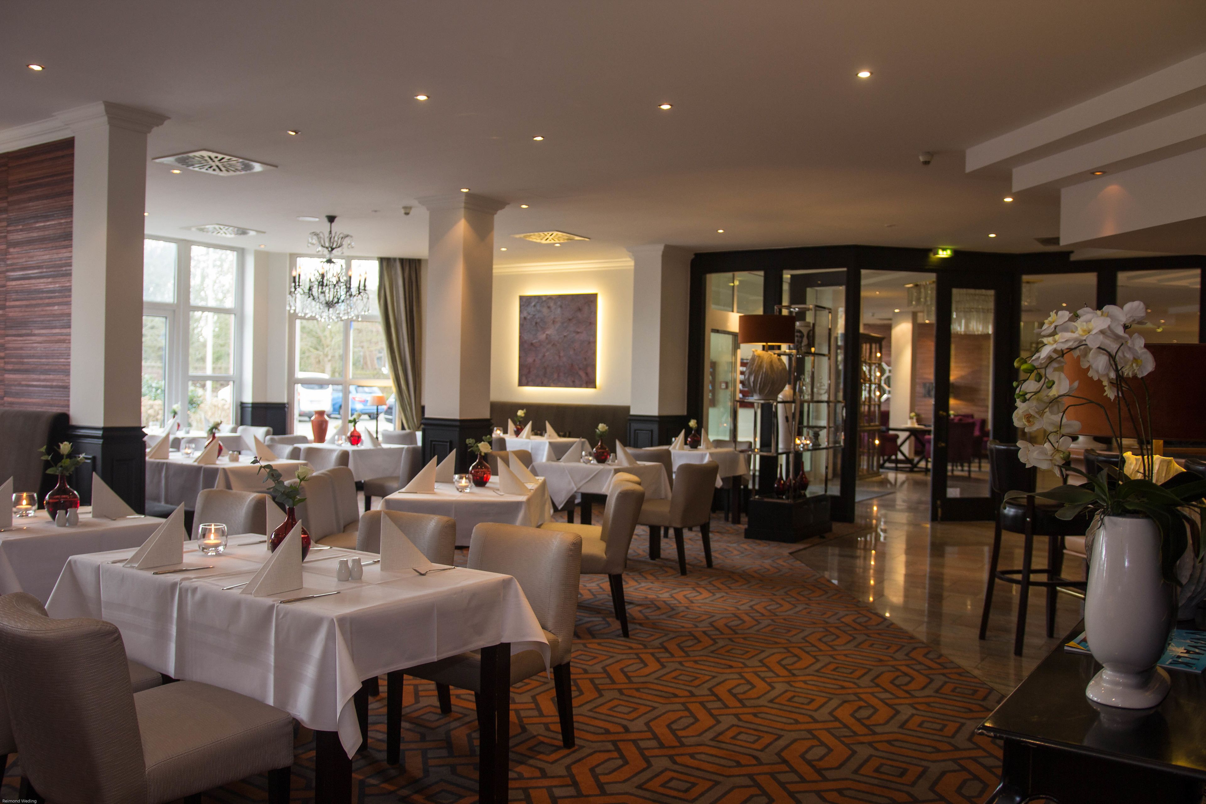 Ein Restaurant mit gedeckten Tischen, einem Kronleuchter und einem gemusterten Boden.