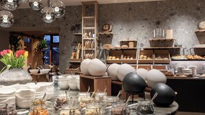 A buffet setup with various food items, a flower arrangement, and a modern interior design. - Hotel Garberhof (Malles Venosta)