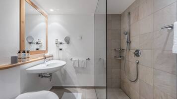 Un bagno moderno con uno specchio grande, un lavandino, un water e una cabina doccia in vetro.
