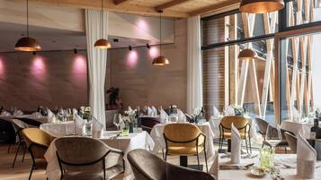 Een restaurant met houten balken, hanglampen en gedekte tafels.