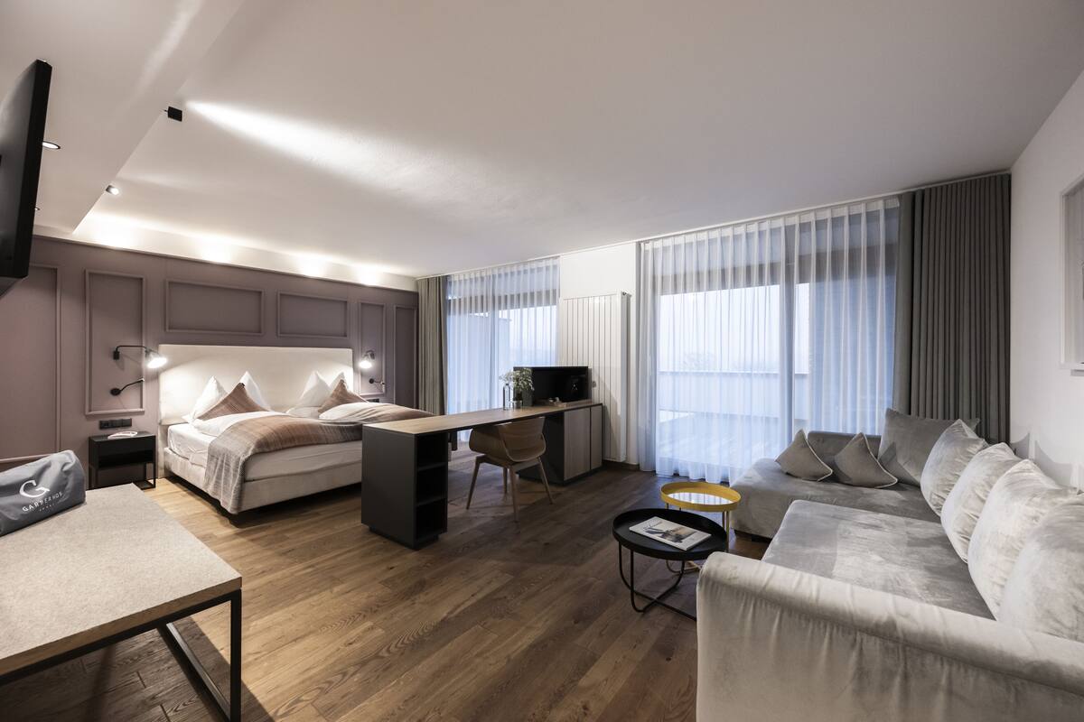 Een moderne hotelkamer met een bed, bureau, bank en televisie.
