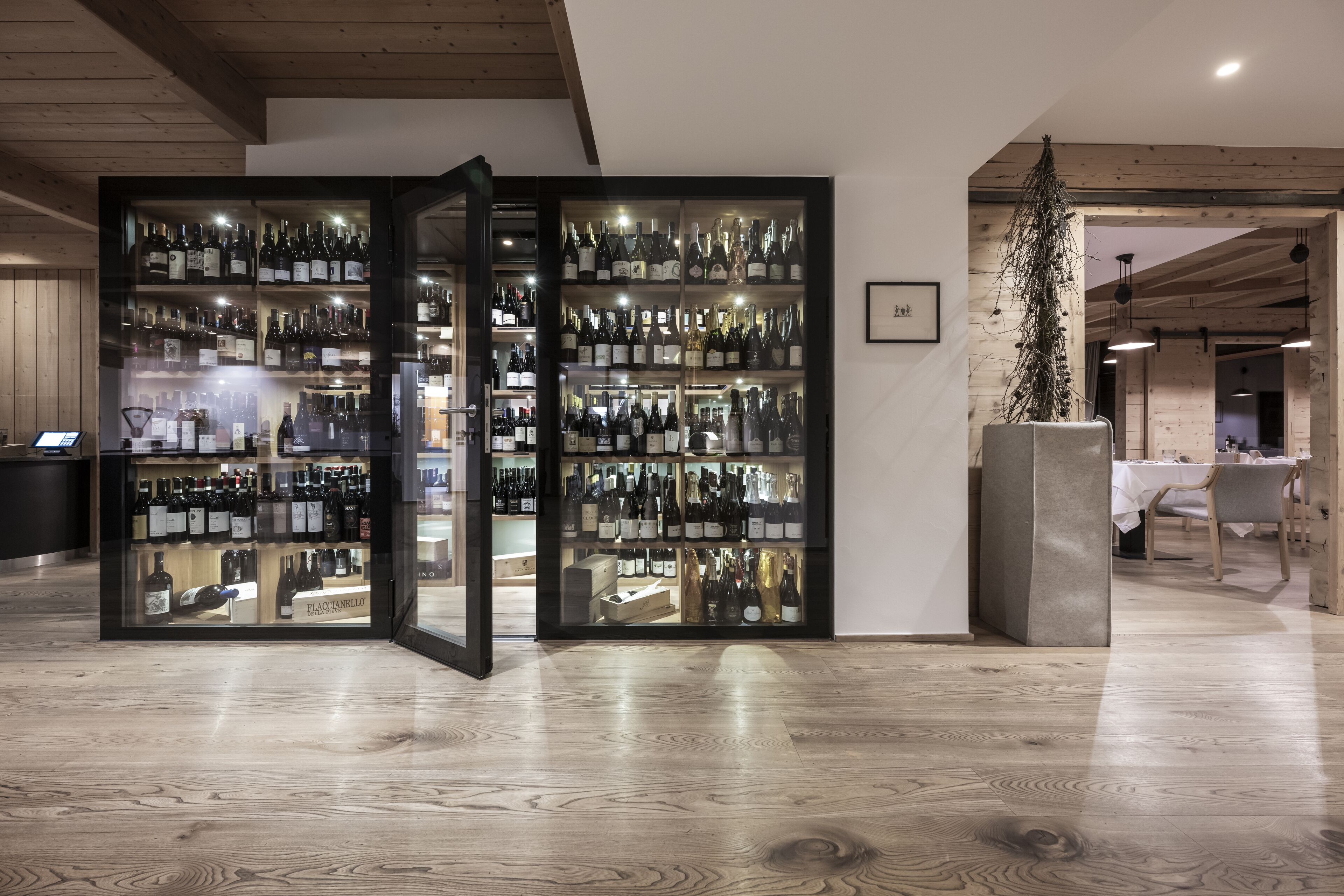 A wine cellar with shelves of wine bottles and a glass door.