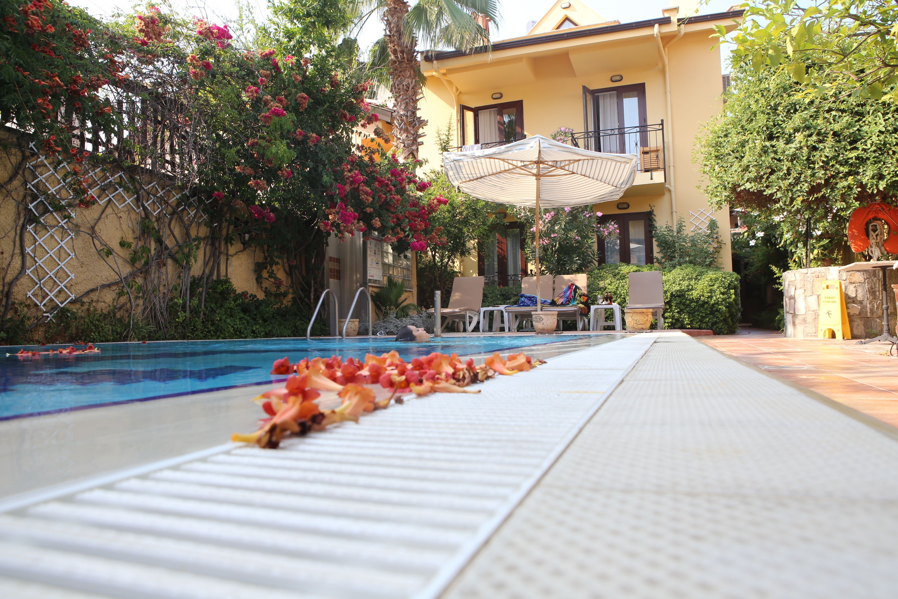 A poolside area with a clear view of the pool, a lounge chair, and a table with an umbrella.
