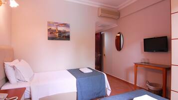 A hotel room with two beds, a television, a painting, and a small table with a telephone.