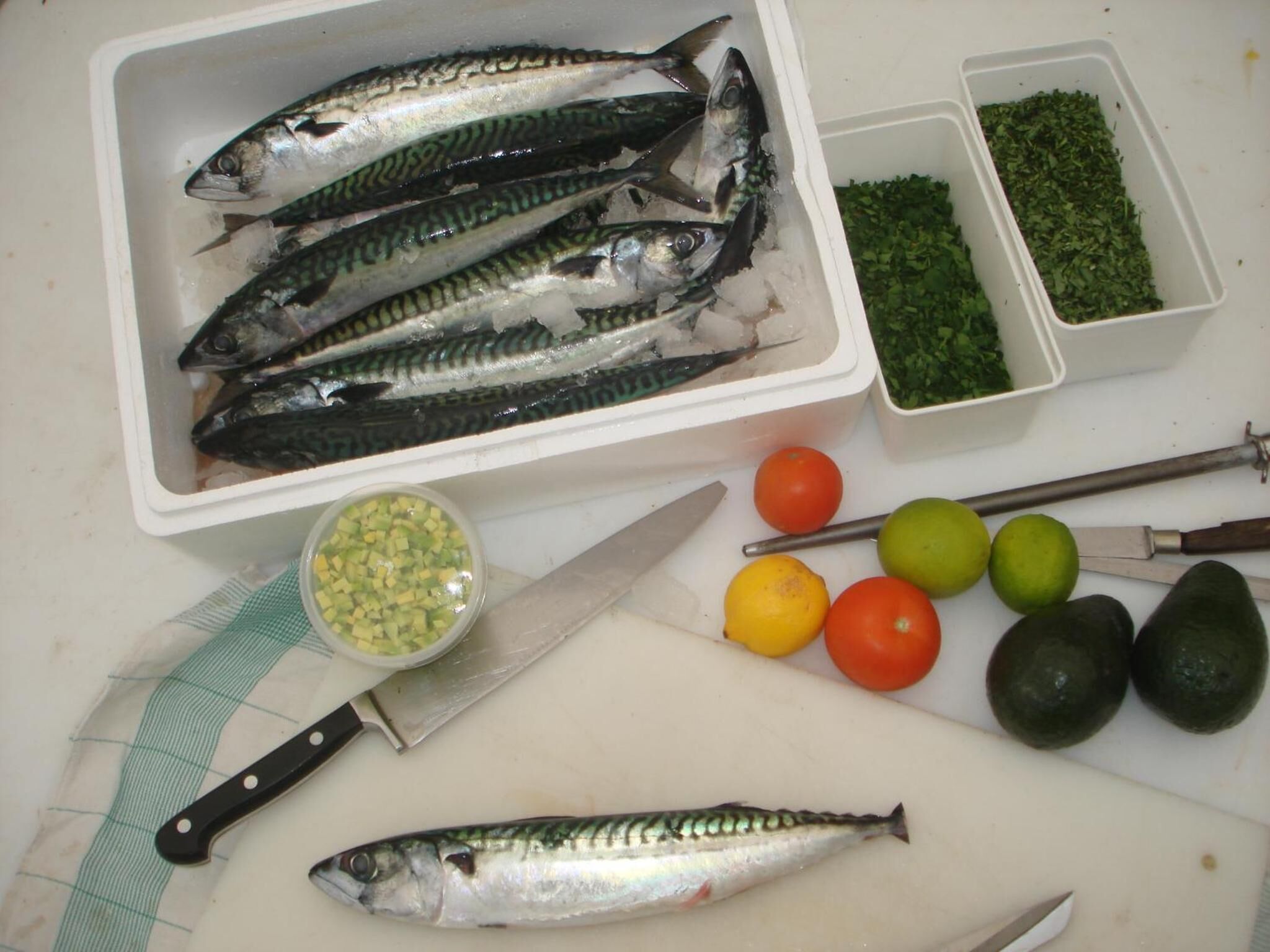 Un plan de travail de cuisine avec du poisson frais, des légumes et des ustensiles de cuisine.