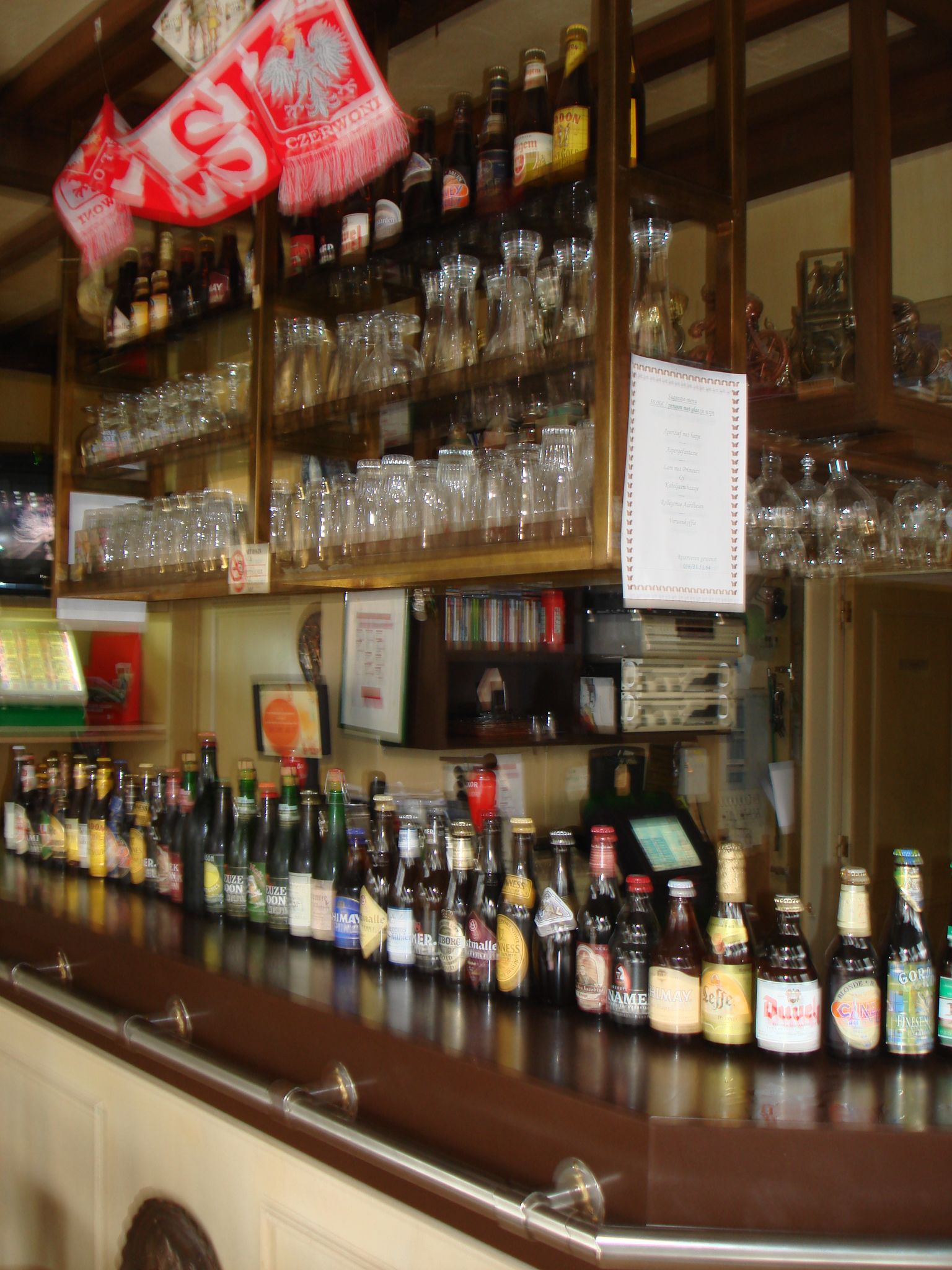 A bar with shelves stocked with various bottles and glasses.