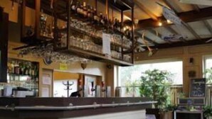 Zona de bar con mostrador, taburetes y vistas al exterior.