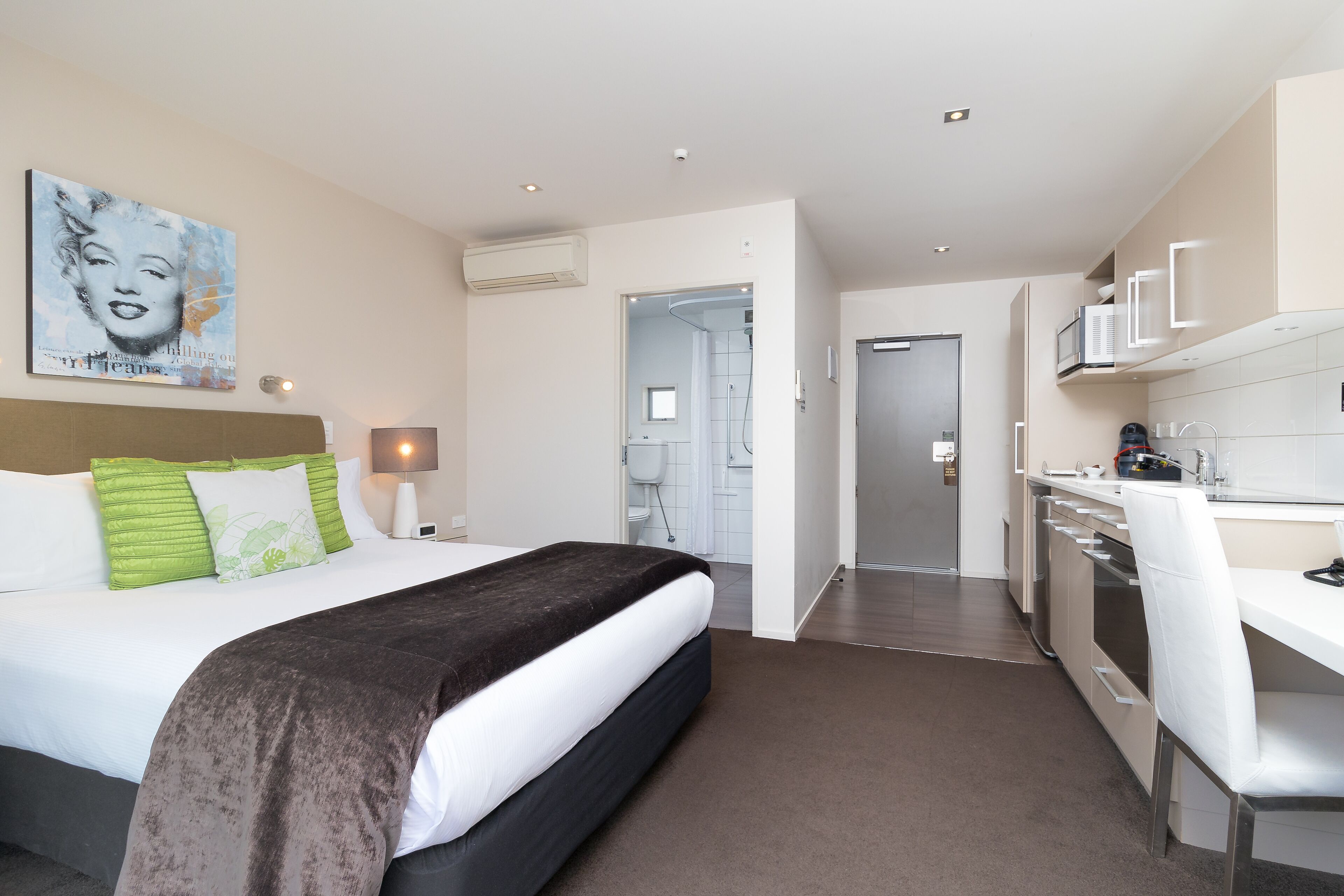 Une chambre d’hôtel moderne équipée d’un grand lit, d’un bureau et d’une kitchenette.