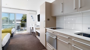 Eine moderne Küche mit großem Fenster, eine Essecke und ein Schlafzimmer mit Balkon.