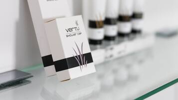 Une sélection de bonnets de douche et de flacons de la marque Veru est exposée sur une étagère en verre.
