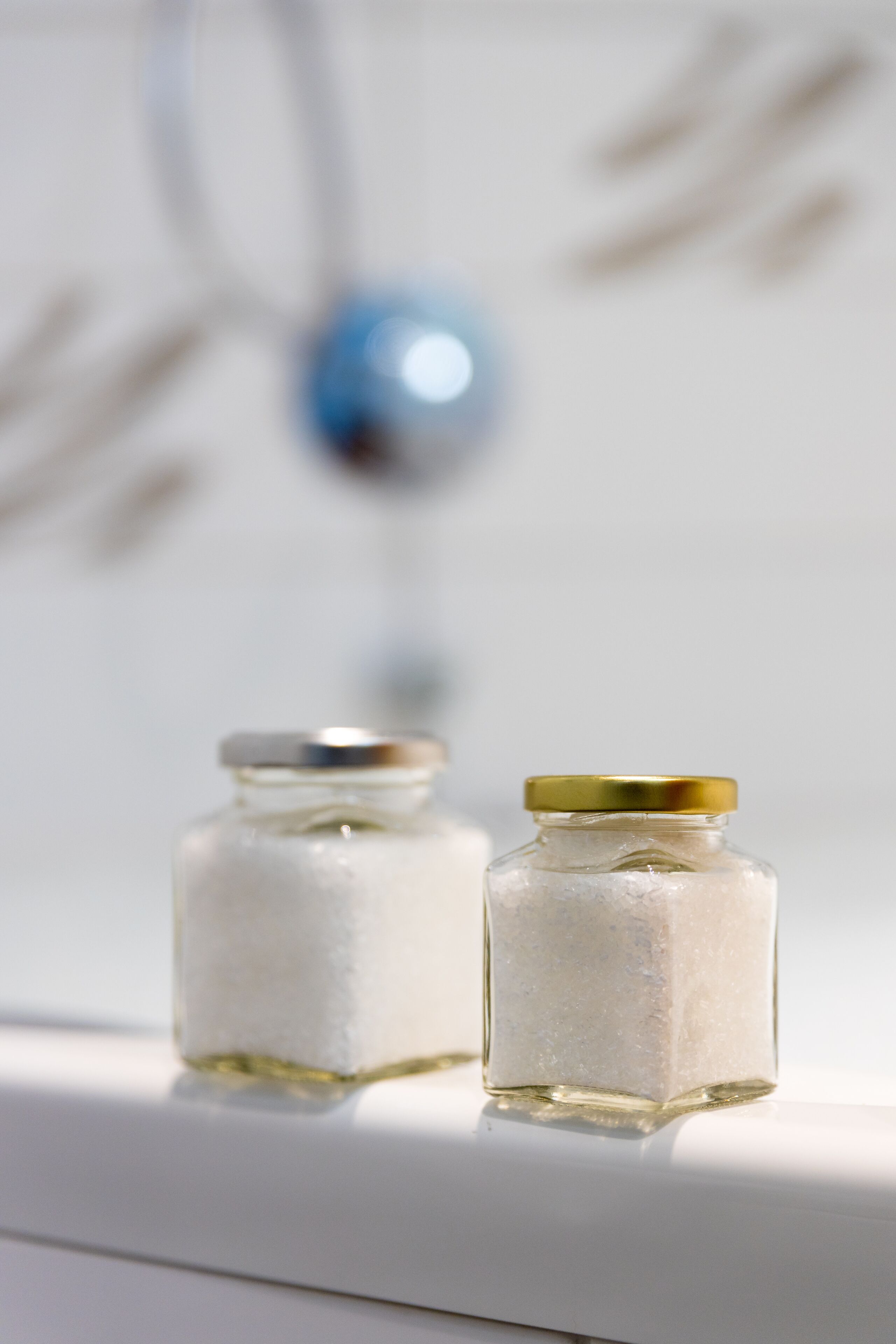 Two small glass jars with gold lids on a white surface.
