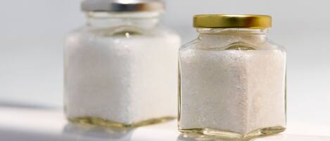 Two small glass jars with gold lids on a white surface.