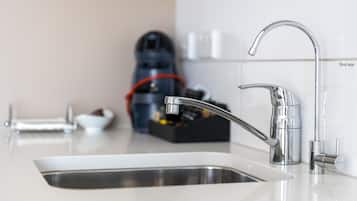 Una cocina moderna con un lavamanos de acero inoxidable, un grifo elegante y una máquina de café al fondo.