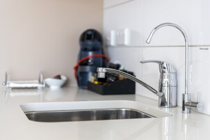 Una cocina moderna con un lavamanos de acero inoxidable, un grifo elegante y una máquina de café al fondo.