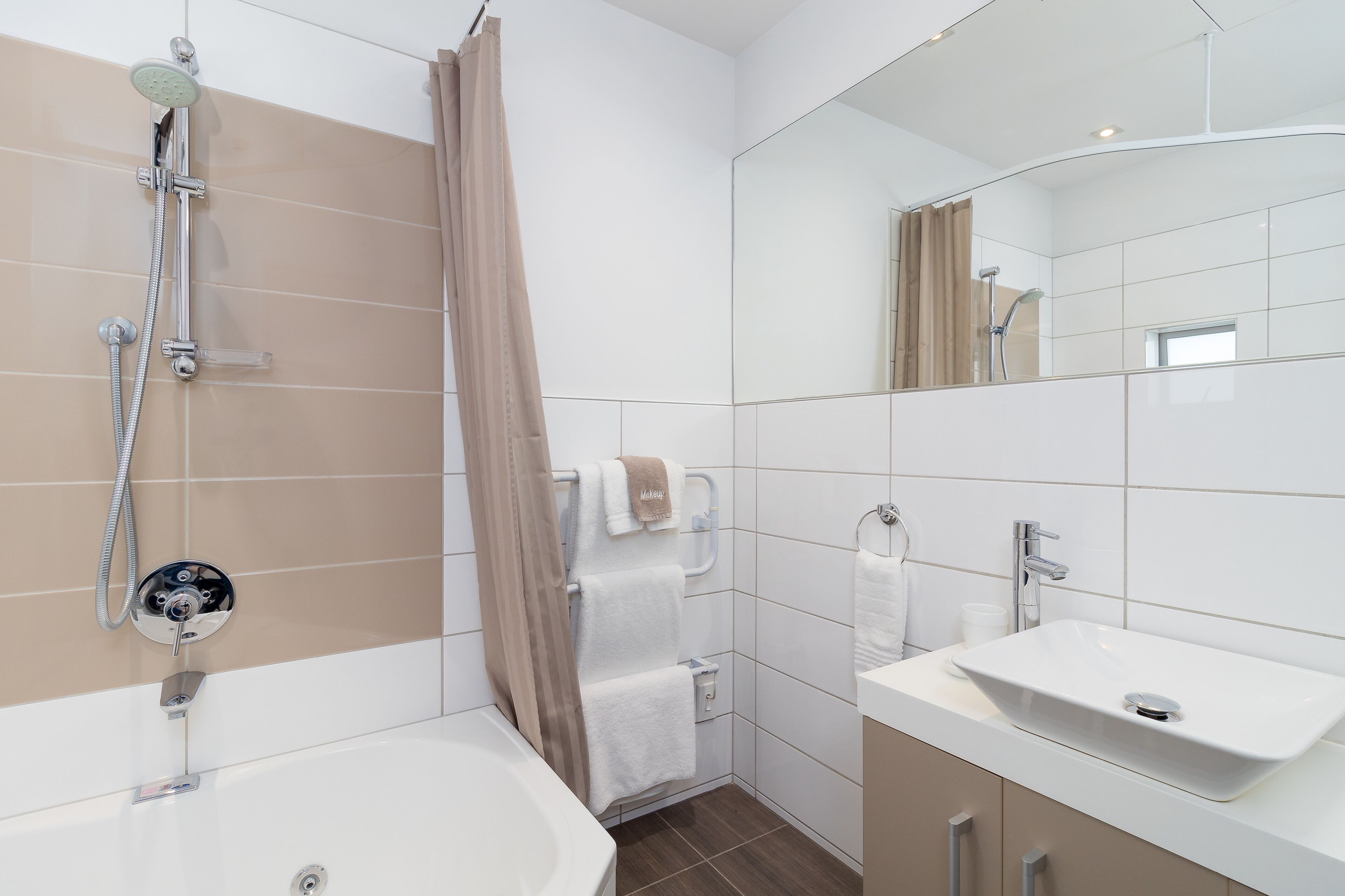 A modern bathroom with a bathtub, shower, and sink.