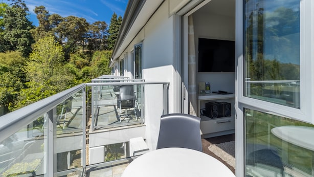 Ein modernes Haus mit Balkon, großen Fenstern und einem Essbereich.