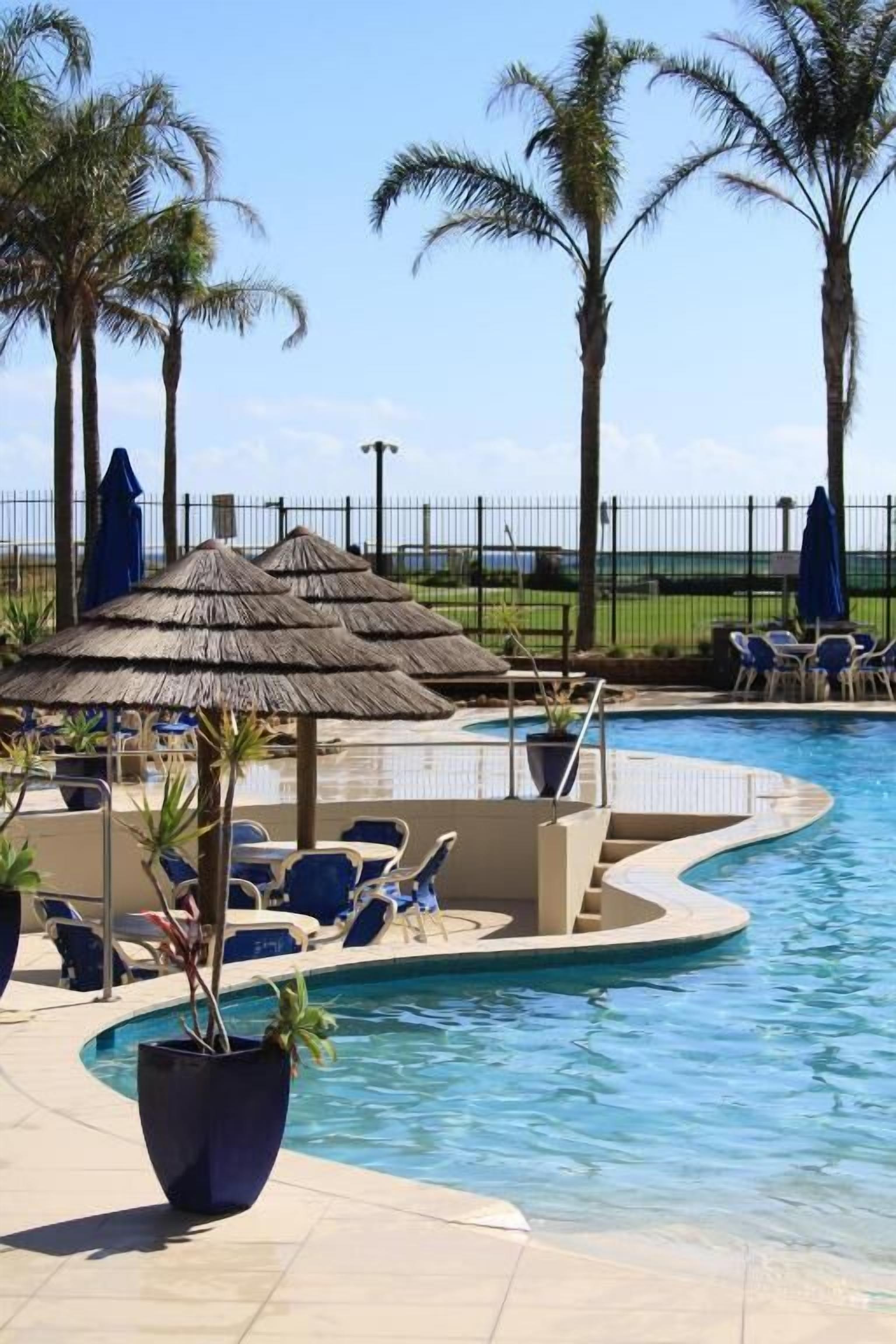 Une piscine avec des chaises longues et des palmiers.
