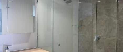 A modern bathroom with a glass-enclosed shower, a sink with a mirror, and white cabinetry.
