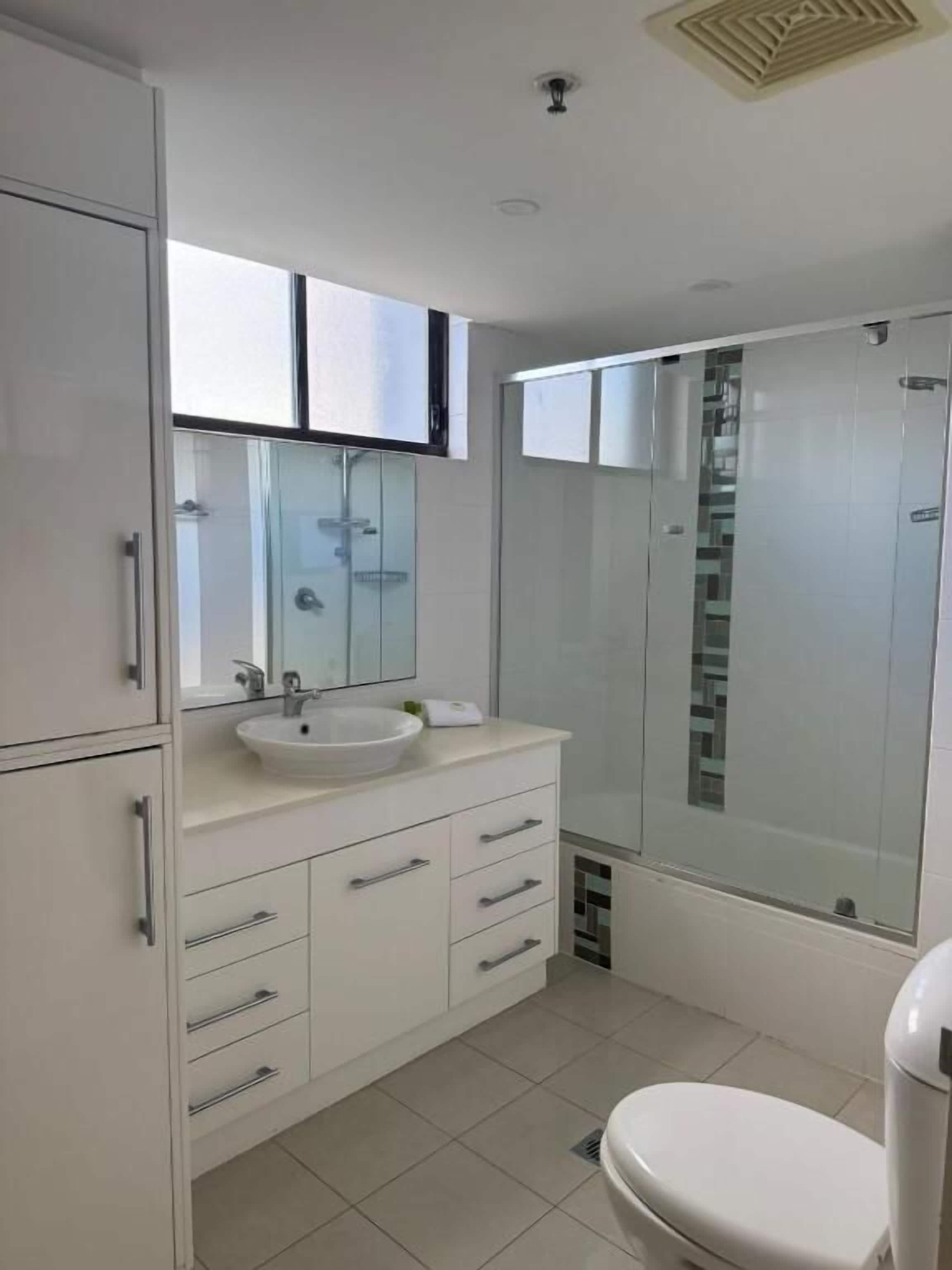 A modern bathroom with a white sink, vanity, and toilet.