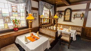 A dining area with wooden benches, white tablecloths, and hanging lamps. - Alte Post (Lehrte)