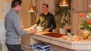 A reception desk with a wooden counter, a plant, and a menu. - Alte Post (Lehrte)