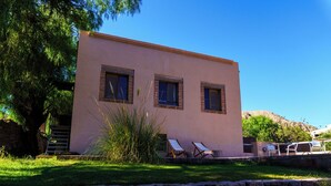 A two-story building with a flat roof, two windows on the second floor, and a small porch area with two lounge chairs. - Patio Alto (Tilcara)
