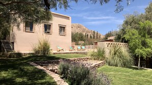 A modern building with a stone facade, a stone pathway, and a grassy lawn with a small garden area. - Patio Alto (Tilcara)