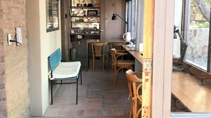 A cozy kitchen with a stone wall, wooden furniture, and a window overlooking a stone wall. - Patio Alto (Tilcara)